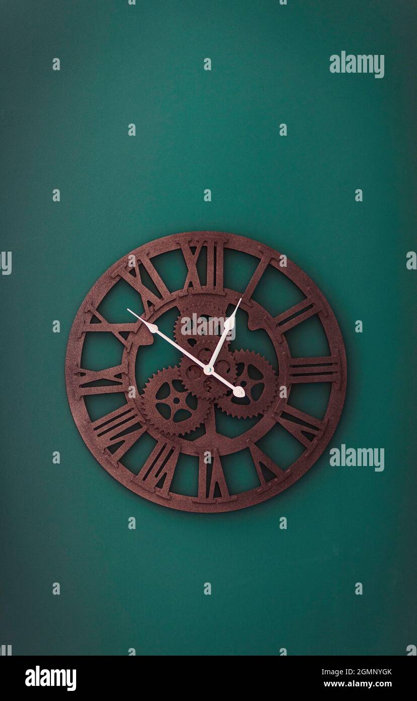 orologio da parete con le mani gialle appese al muro. Immagine minimalista e piatta di orologio da parete in plastica su sfondo turquioso verde con spazio copia e. Foto Stock