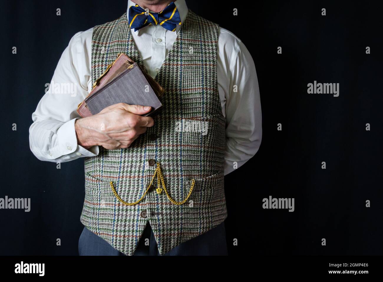 Gentleman intelligente in gilet twed e Bow Tie Holding Old Books. Amante della letteratura e della lettura. Foto Stock