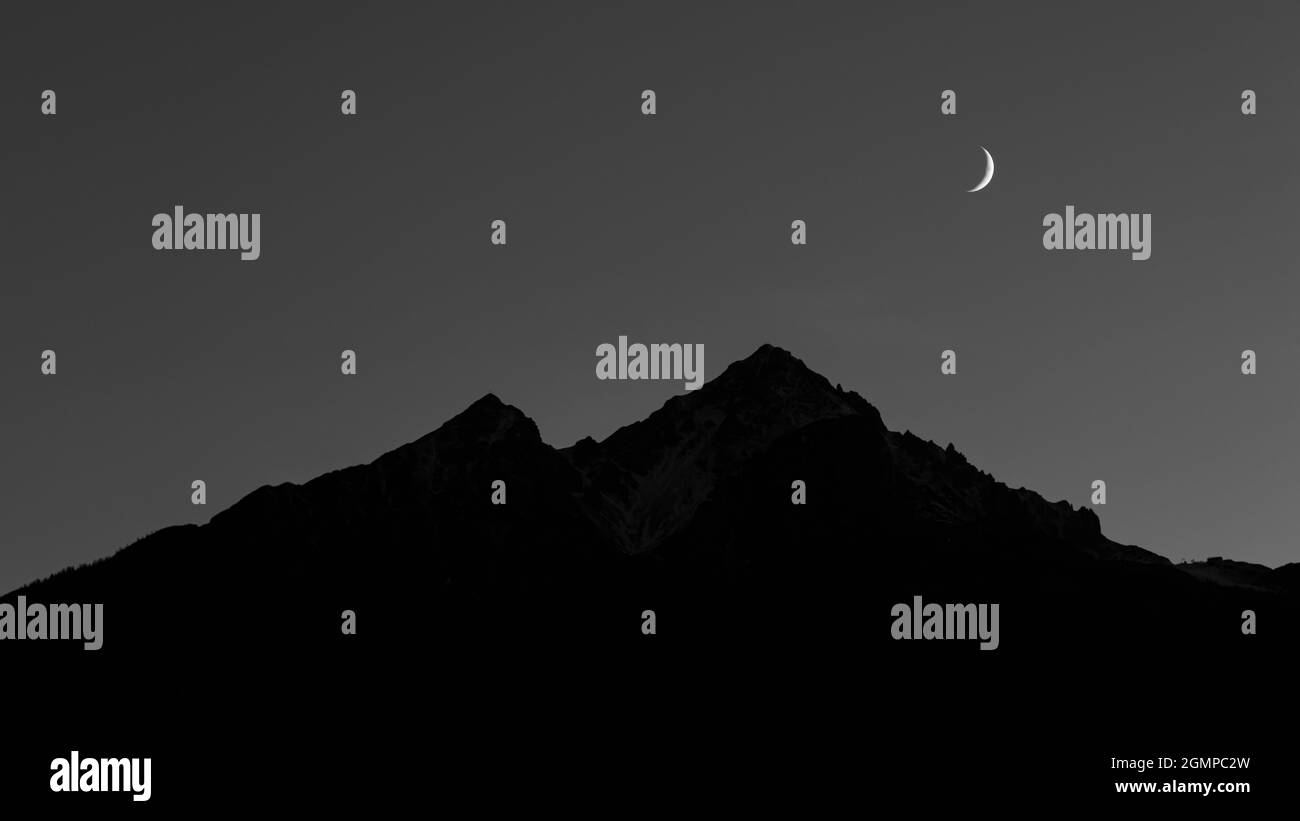 Luna sopra silhouette di montagna scura Foto Stock