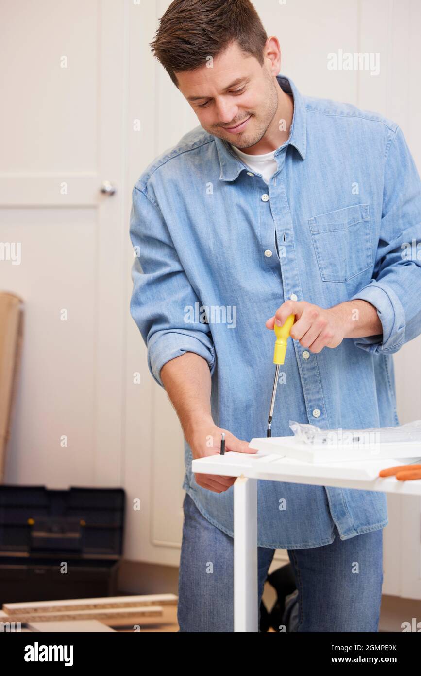 L'uomo che mette insieme il mobile di auto-assemblaggio a casa Foto Stock