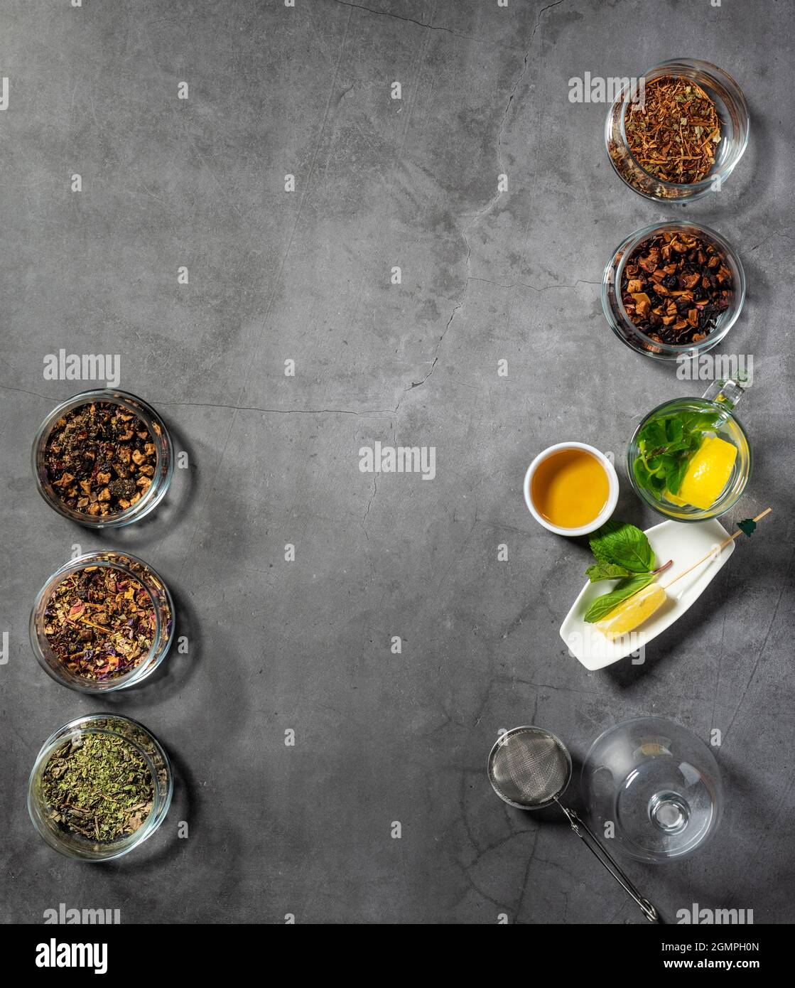 Layout creativo con tè, tè verde, tè nero e vari tipi di frutta e tisane su sfondo di pietra scura. Posa piana. Foto Stock
