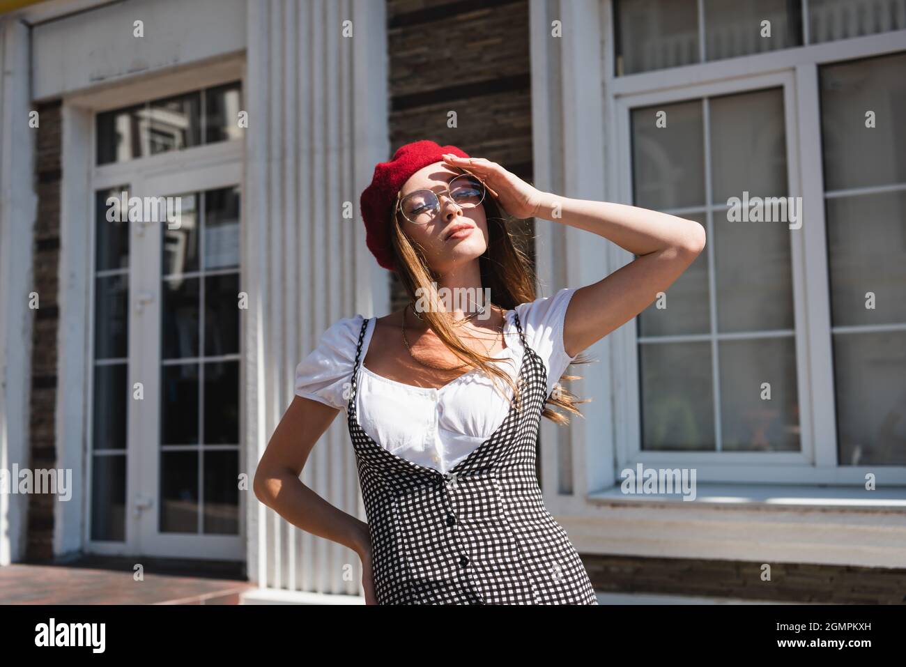 giovane donna in berretto rosso e occhiali che coprono il viso dal sole Foto Stock