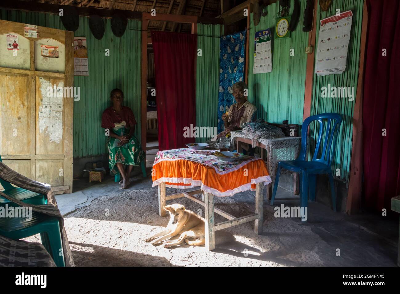 Interno di una piccola casa di bambù con nonna e nonno seduti su una sedia e cane sotto il tavolo. Villaggio di Oinlasi, Timor Ovest, Indonesia. Foto Stock