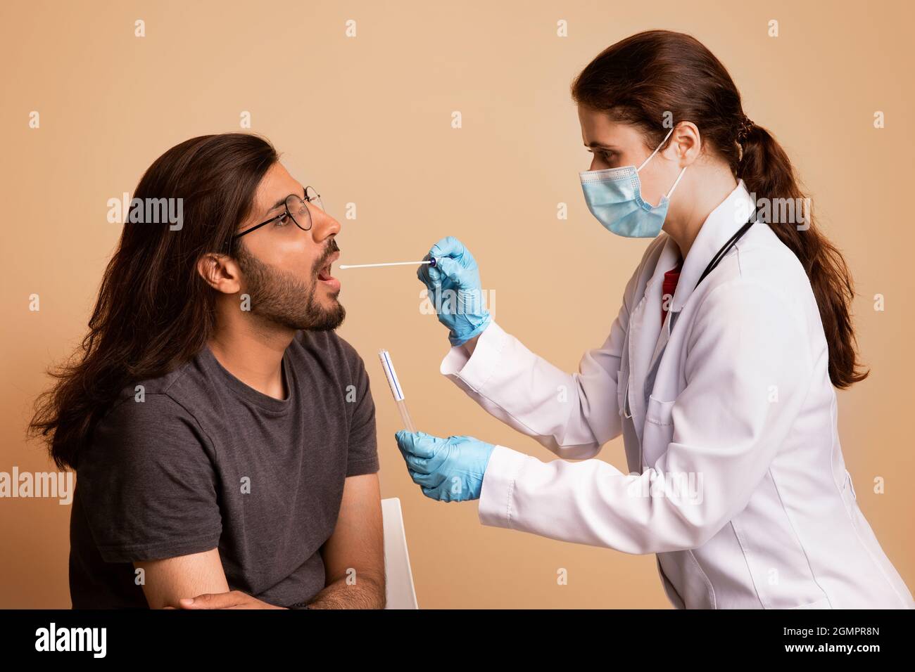 Medico femminile che fa PCR-test per il ragazzo arabo in clinica Foto Stock