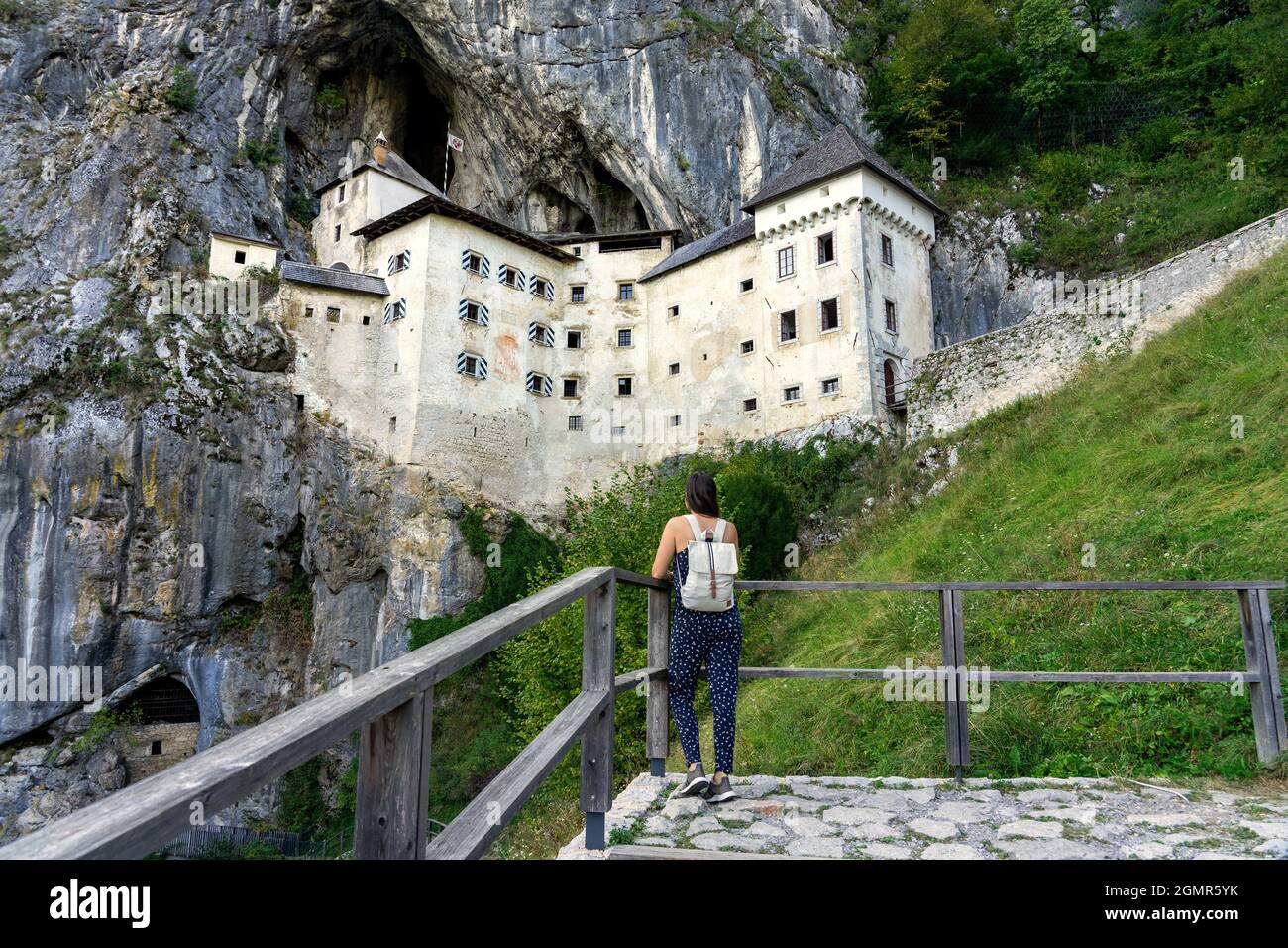 castello predjama costruito in una montagna nella natura vicino alla grotta postojna con una donna turistica che lo guarda . Foto Stock