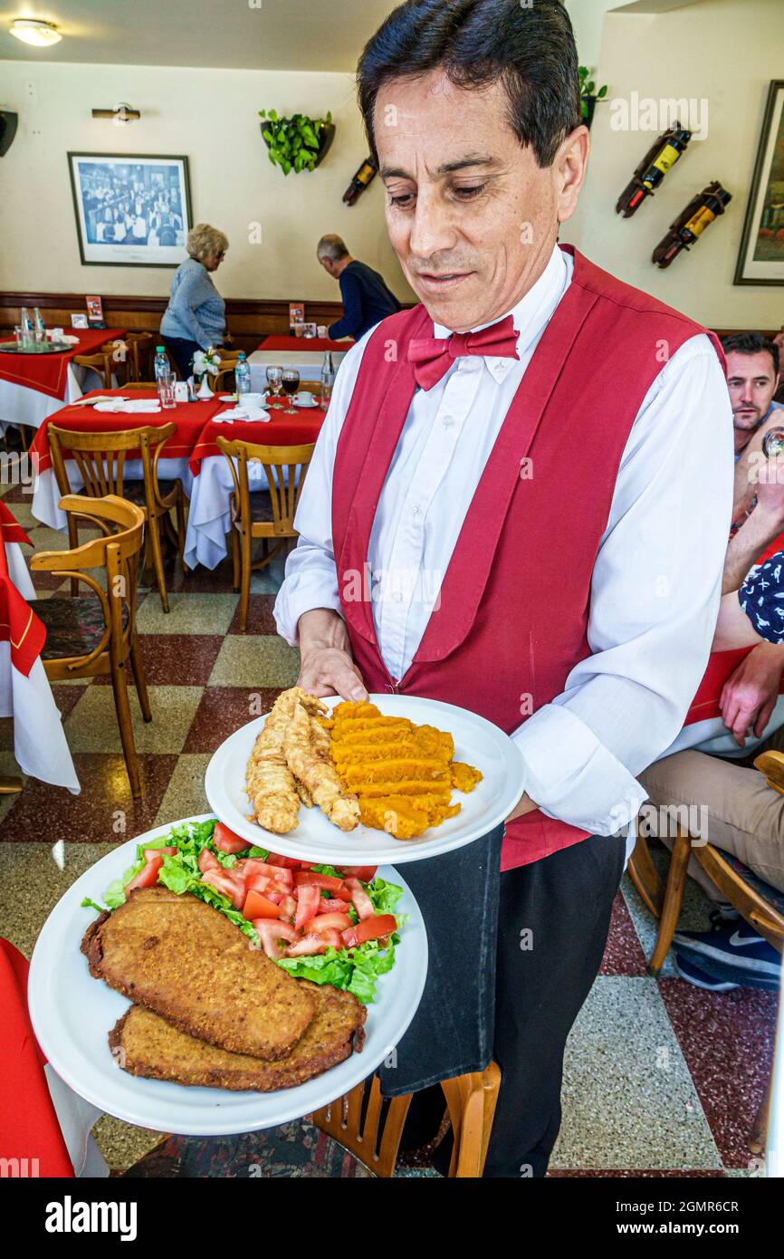 Buenos Aires Argentina,Paseo de las Luces Ristorante Confiteria ristorante ispanico uomo maschio, cameriere server interno serve piatti da cucina indossare uniforme Foto Stock