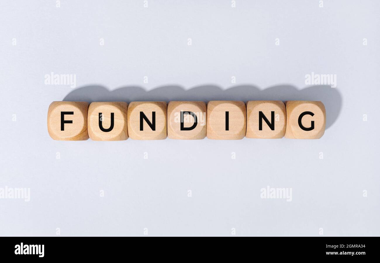 Parola di finanziamento su blocco di legno isolato su sfondo grigio Foto Stock