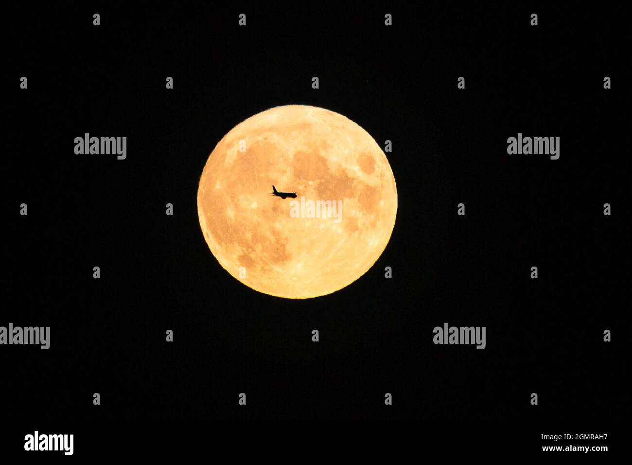 Birmingham, Regno Unito. 20 Settembre 2021. Un aereo di volo notturno passa sopra la luna di raccolto incandescente mentre sorge sopra la città di Birmingham, Regno Unito. Credit: Peter Lopeman/Alamy Live News Foto Stock