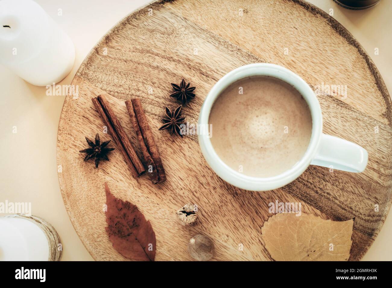 Una tazza di caffè con anice stellato, noce moscata e bastoncini di cannella su un vassoio di legno piatto d'autunno, bevanda calda, casa accogliente. Vista dall'alto Foto Stock