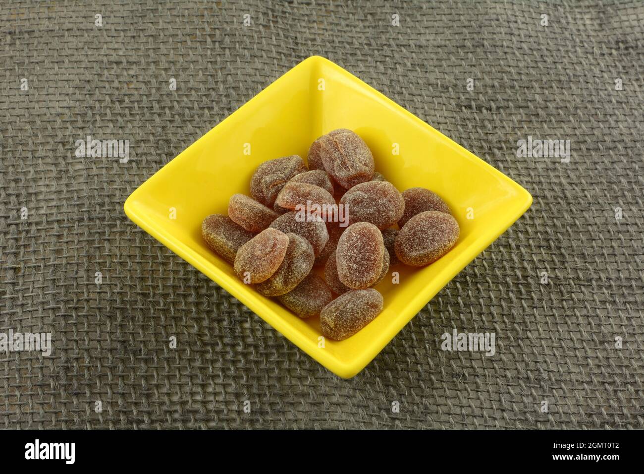 Pastiglie di bacche miste in caramelle gialle su tela grigia Foto Stock