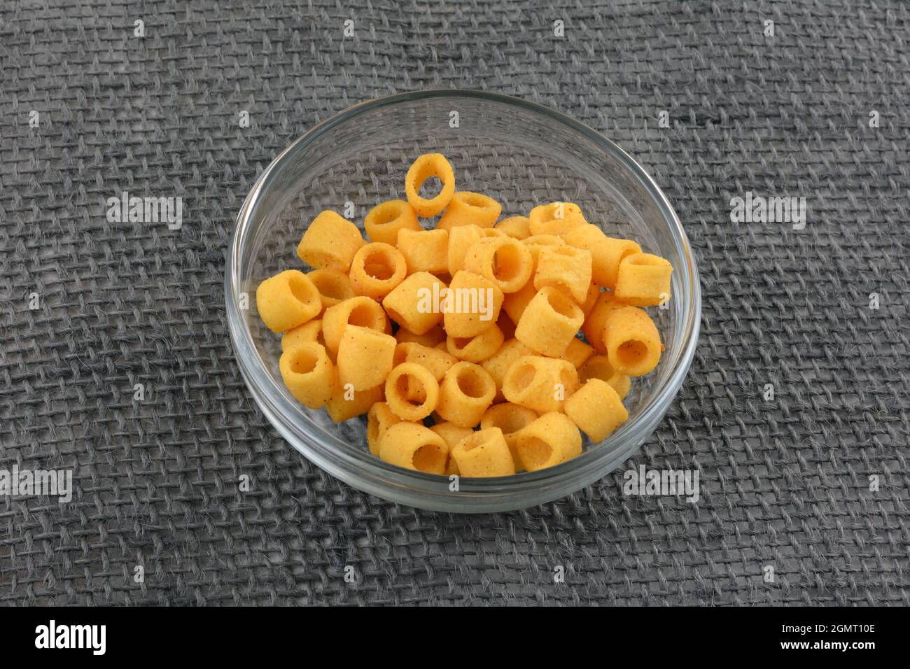Croccanti anelli di patate alla griglia in una ciotola di vetro su tela grigia Foto Stock
