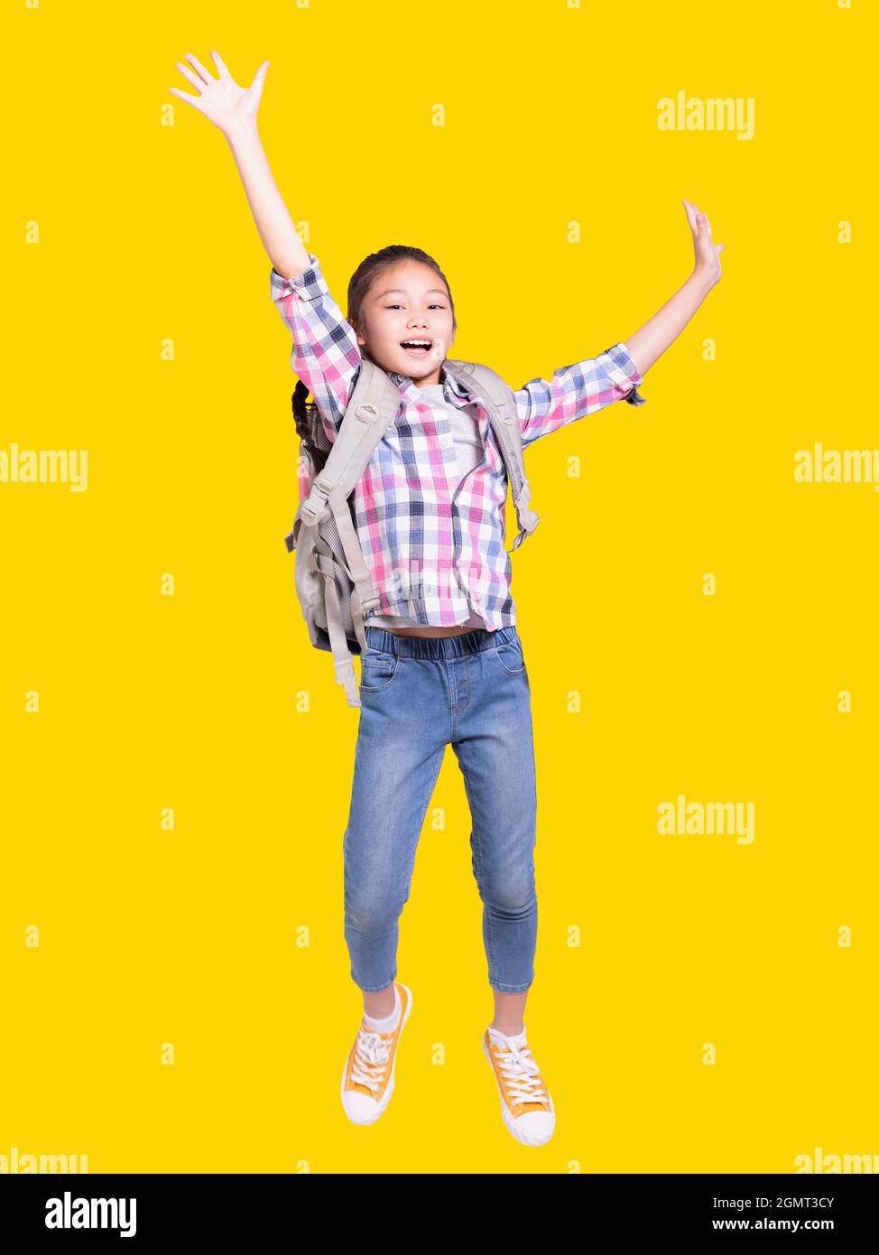 Ritratto completo di una ragazza felice studente con borsa e jumping.isolated su sfondo giallo. Foto Stock