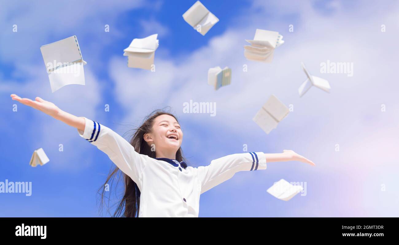 Felice scuola ragazza studente lancio libri volare in aria Foto Stock