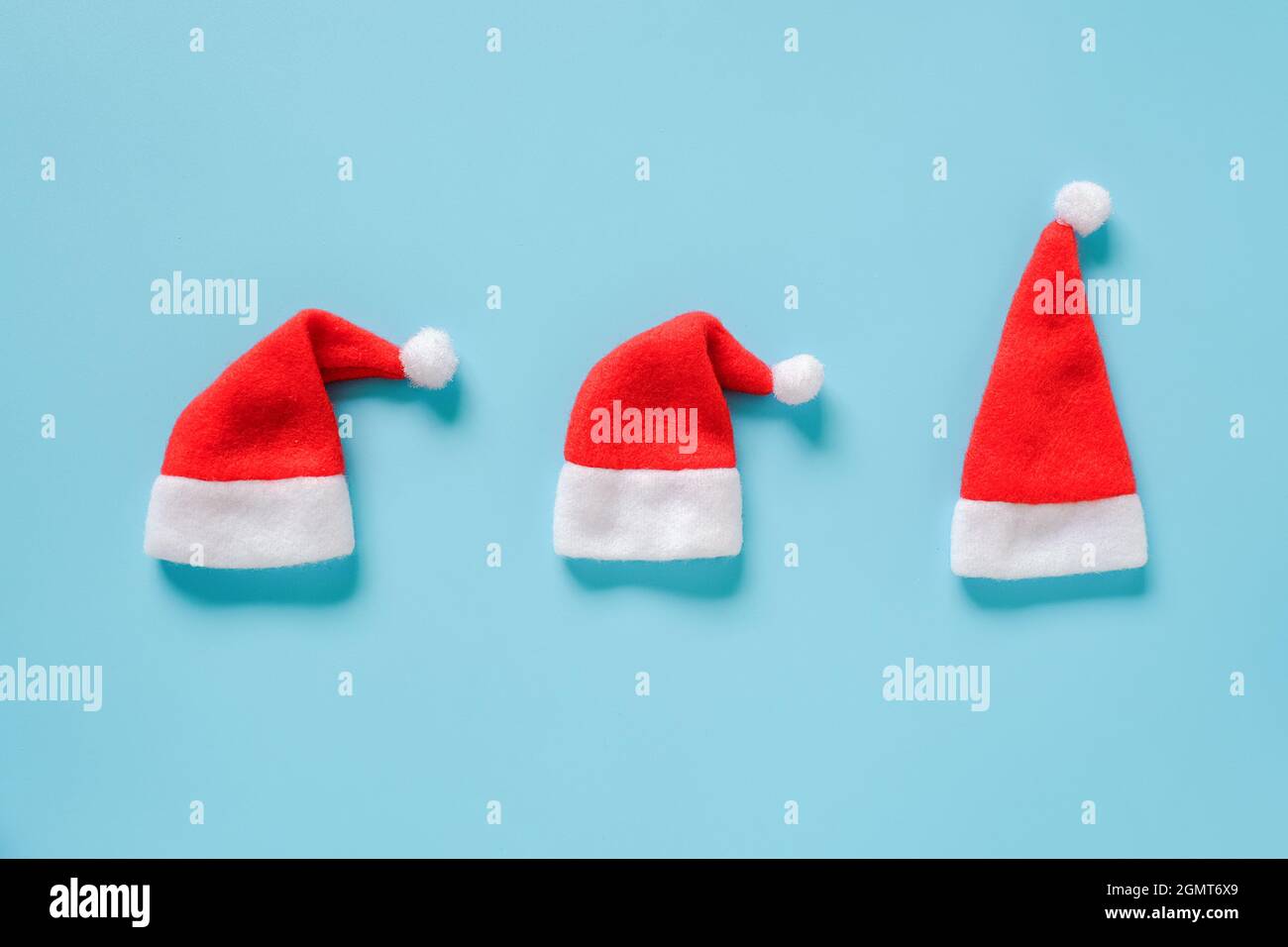 Composizione delle vacanze invernali. Tre cappelli rossi Babbo Natale su sfondo blu. Layout biglietto d'auguri Vista dall'alto Template piatto per design, card, invitatio Foto Stock