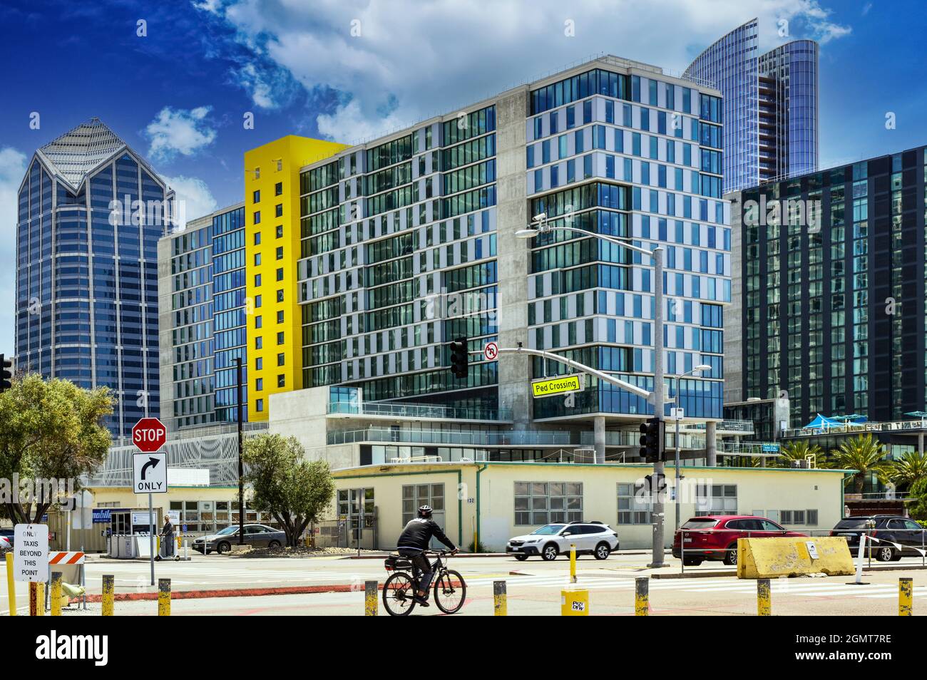 Un paesaggio urbano moderno e alla moda con alti condomini ed edifici con un bicyclist in crosswalk vicino al lato della baia sulla Pacific Highway a San Diego, CA Foto Stock