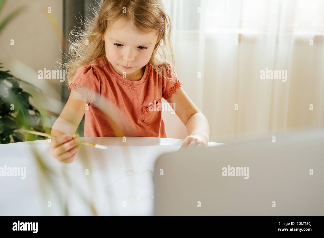 Giovane ragazza cute che spende un tempo disegnare usando le lezioni in linea sul laptop. Apprendimento a distanza, formazione online. Foto Stock