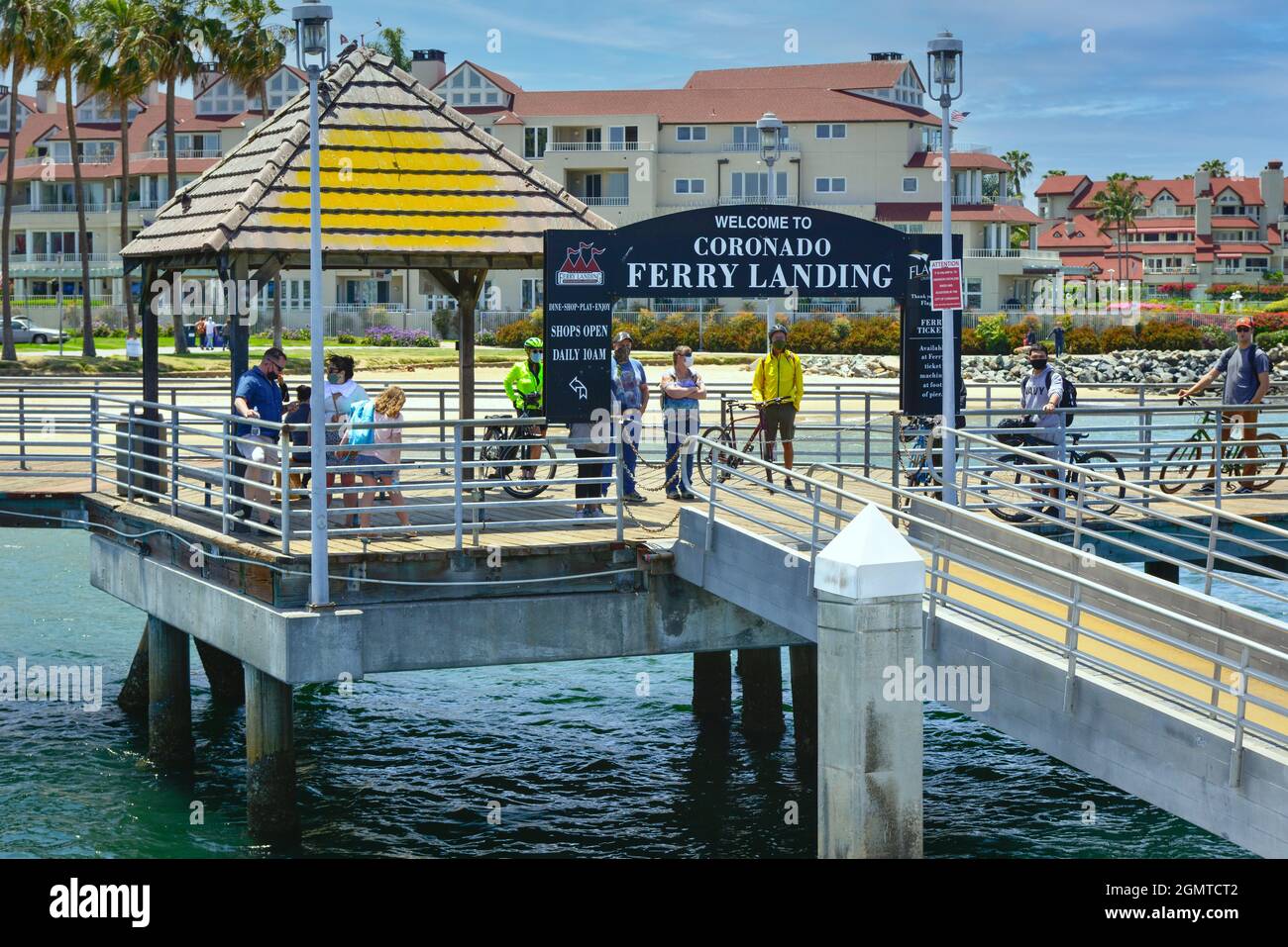 Le persone, alcune in bicicletta, attendono al molo di carico del traghetto per l'arrivo del traghetto Coronado per viaggiare attraverso la baia di San Diego fino al molo di San Diego Foto Stock