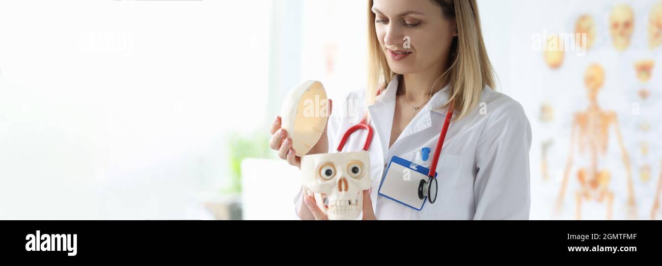 La dottoressa in camice bianco sta tenendo manichino di essere umano cranio Foto Stock