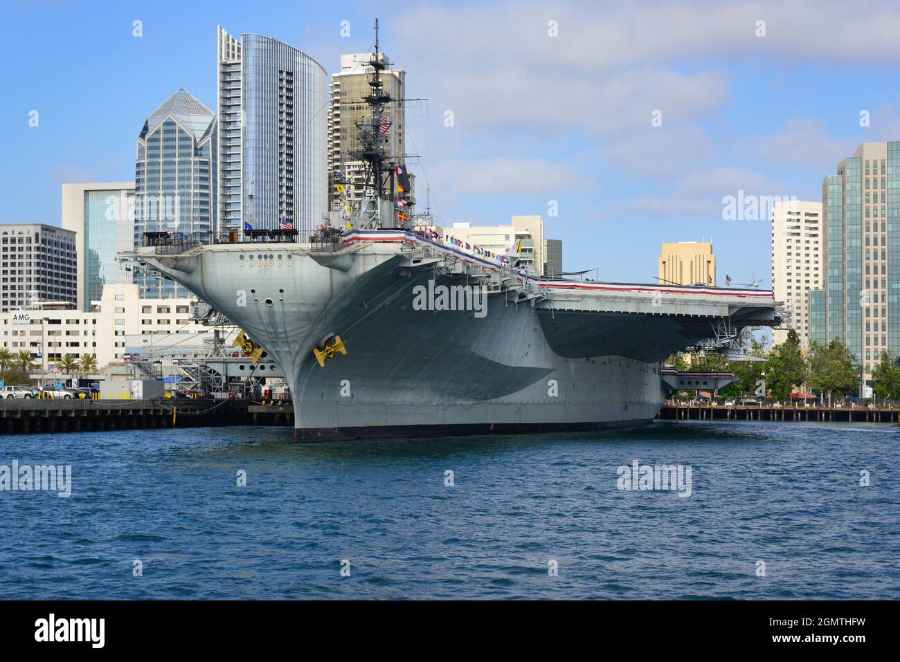 La USS Midway, la storica corazzata portaerei, ora museo, galleggia nel porto di San Diego con lo skyline del centro in background, San Dieg Foto Stock