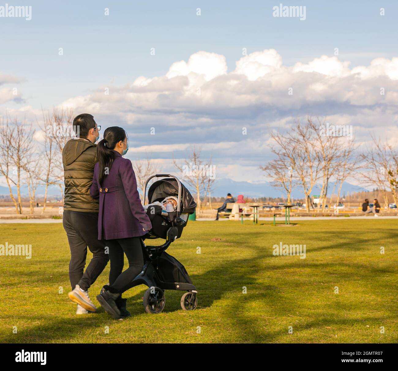 Coppia asiatica che cammina in un parco con il loro bambino in un passeggino cariage. Foto Stock
