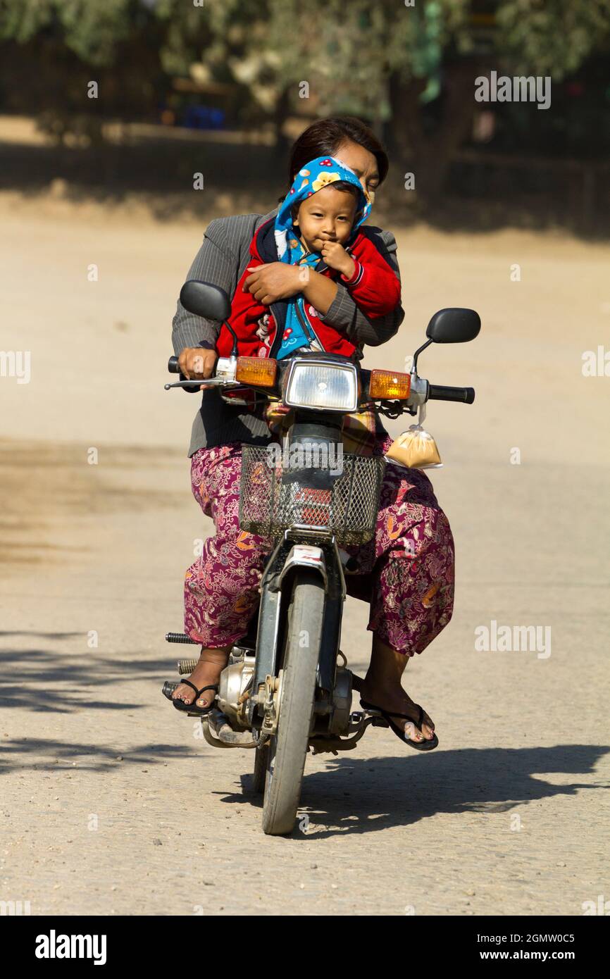 Bagan, Myanmar - 29 Gennaio 2013 scena quotidiana in una strada trafficata in Myanmar. Due su un ciclomotore - bambino e padre, arroccato precario. Niente preoccupazioni. Che cosa Foto Stock