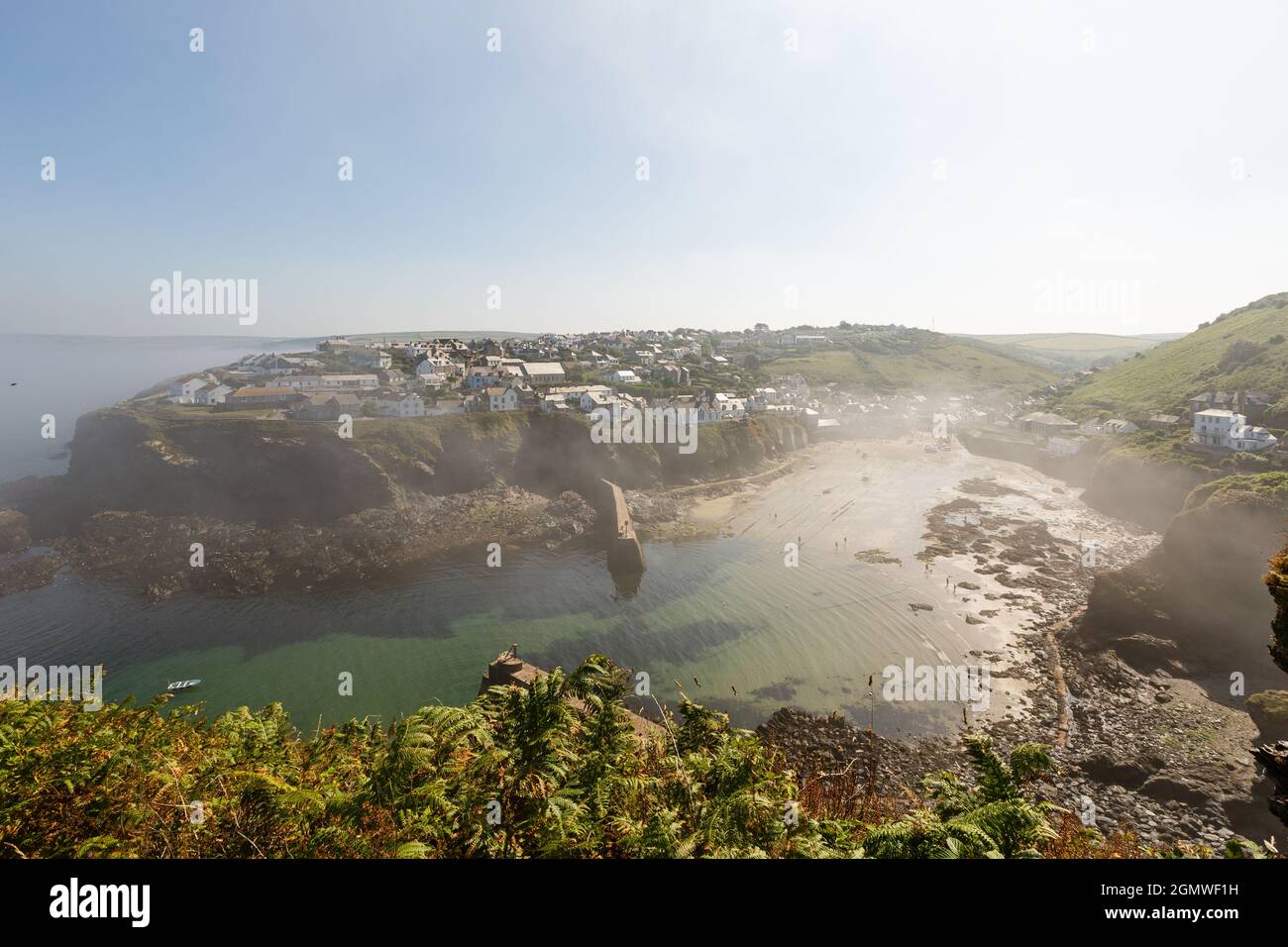 La nebbia marina copre in parte il porto di Port Isaac, con bassa marea. Foto Stock