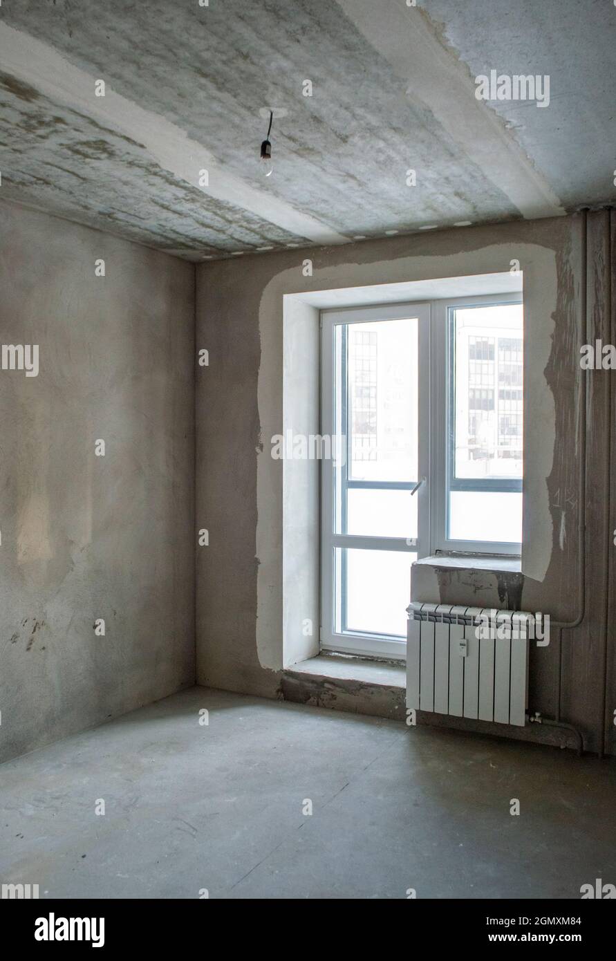Edificio non finito. Finitura ruvida dell'appartamento. Camera con pareti in cemento intonacato. Foto Stock
