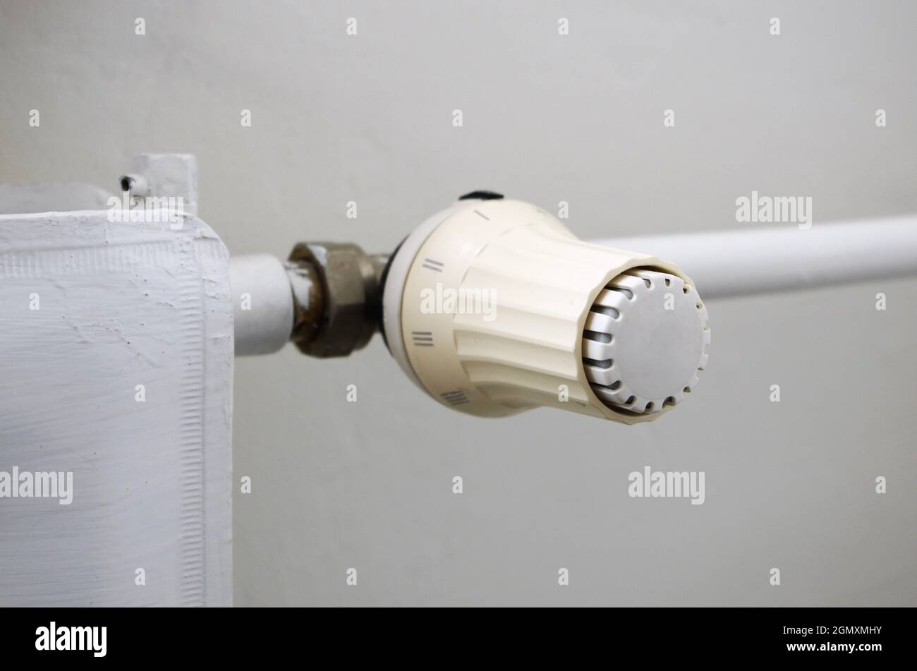 Prezzi del calore e concetto di crisi energetica. La manopola di regolazione della temperatura del radiatore di riscaldamento, il termostato, riduce i costi di riscaldamento. Foto Stock