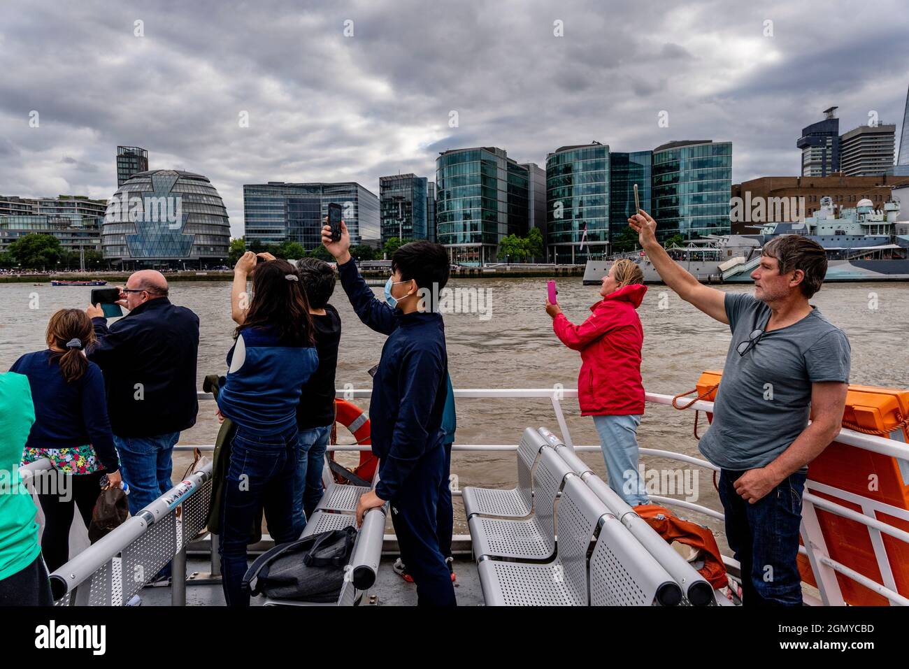 Un gruppo di persone su Un Tamigi River Cruiser scattare foto con i loro telefoni cellulari (cellulari), Londra, Regno Unito. Foto Stock