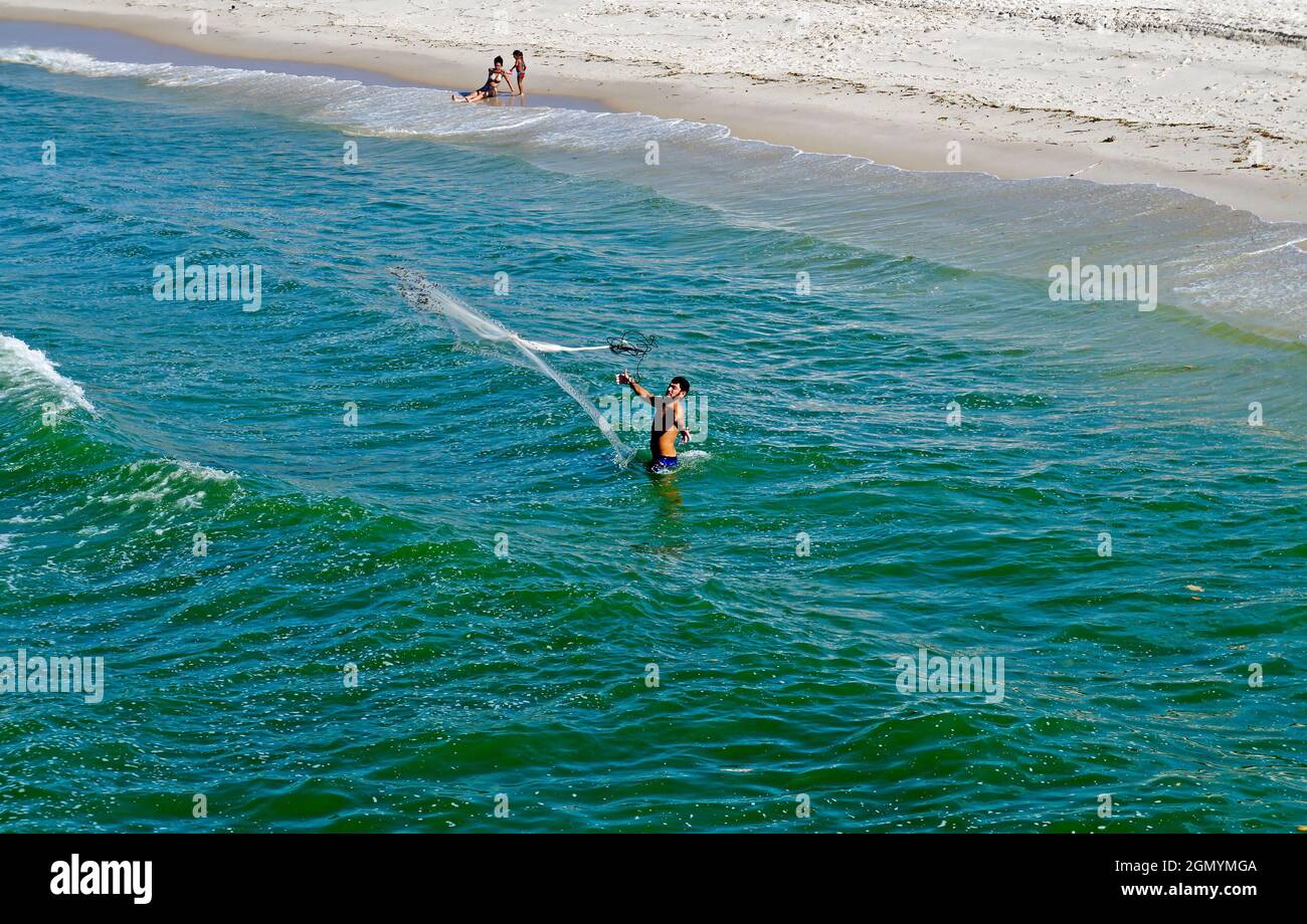 RIO DE JANEIRO, BRASILE - 25 MARZO 2017: Uomo che pesca con la rete nelle acque della spiaggia barra da Tijuca Foto Stock