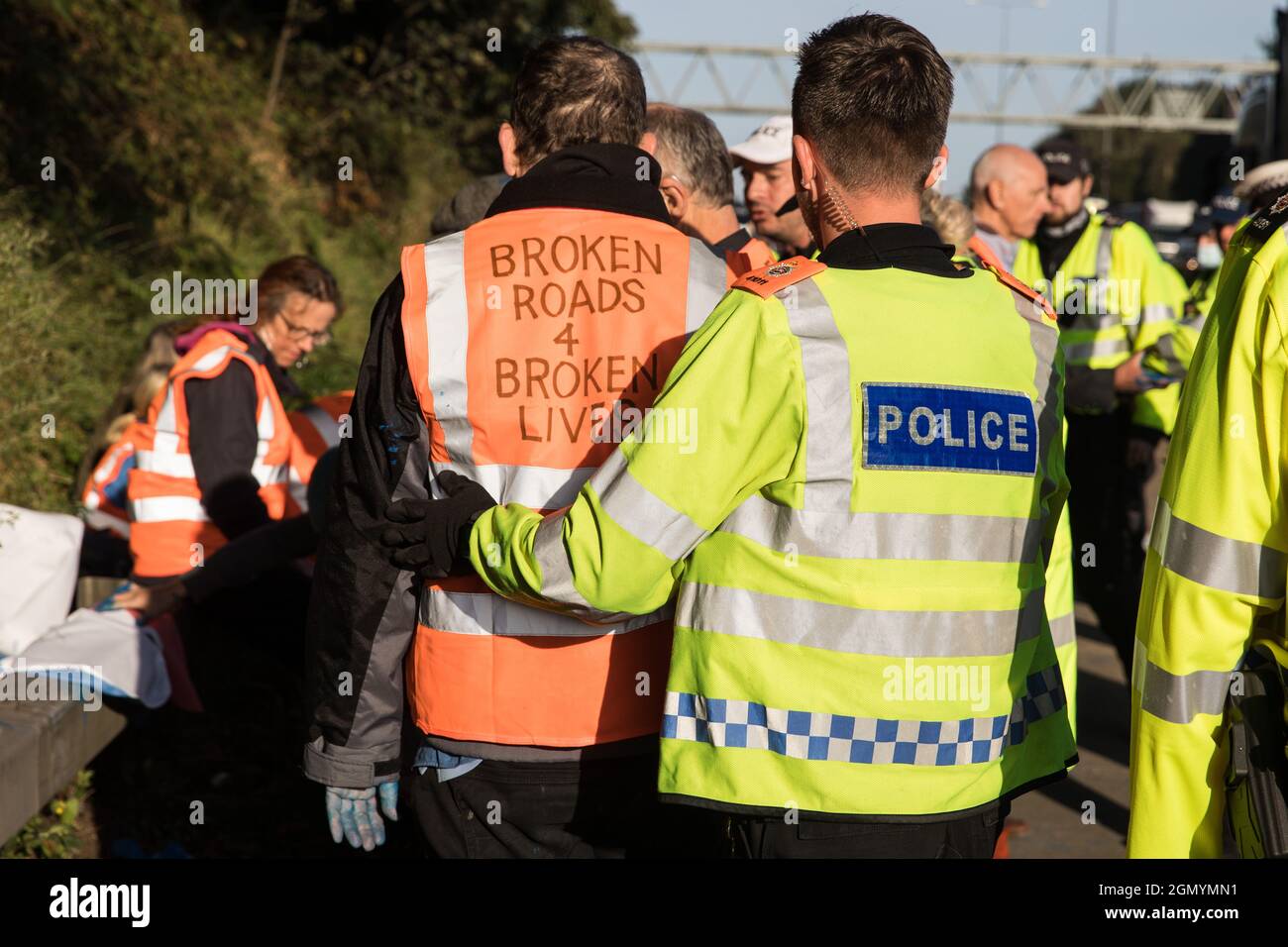 Ockham, Regno Unito. 21 Settembre 2021. Gli ufficiali della polizia di Surrey monitorano gli attivisti climatici insulati della Gran Bretagna che avevano bloccato la carreggiata in senso orario della M25 tra gli svincoli 9 e 10 come parte di una campagna volta a spingere il governo del Regno Unito a compiere significativi cambiamenti legislativi per iniziare a ridurre le emissioni. Entrambe le carreggiate sono state bloccate brevemente prima di essere sgombrate dalla polizia di Surrey. Gli attivisti chiedono che il governo prometta immediatamente sia di finanziare e garantire l'isolamento di tutti gli alloggi sociali in Gran Bretagna entro il 2025 e di produrre entro quattro mesi un p nazionale giuridicamente vincolante Foto Stock