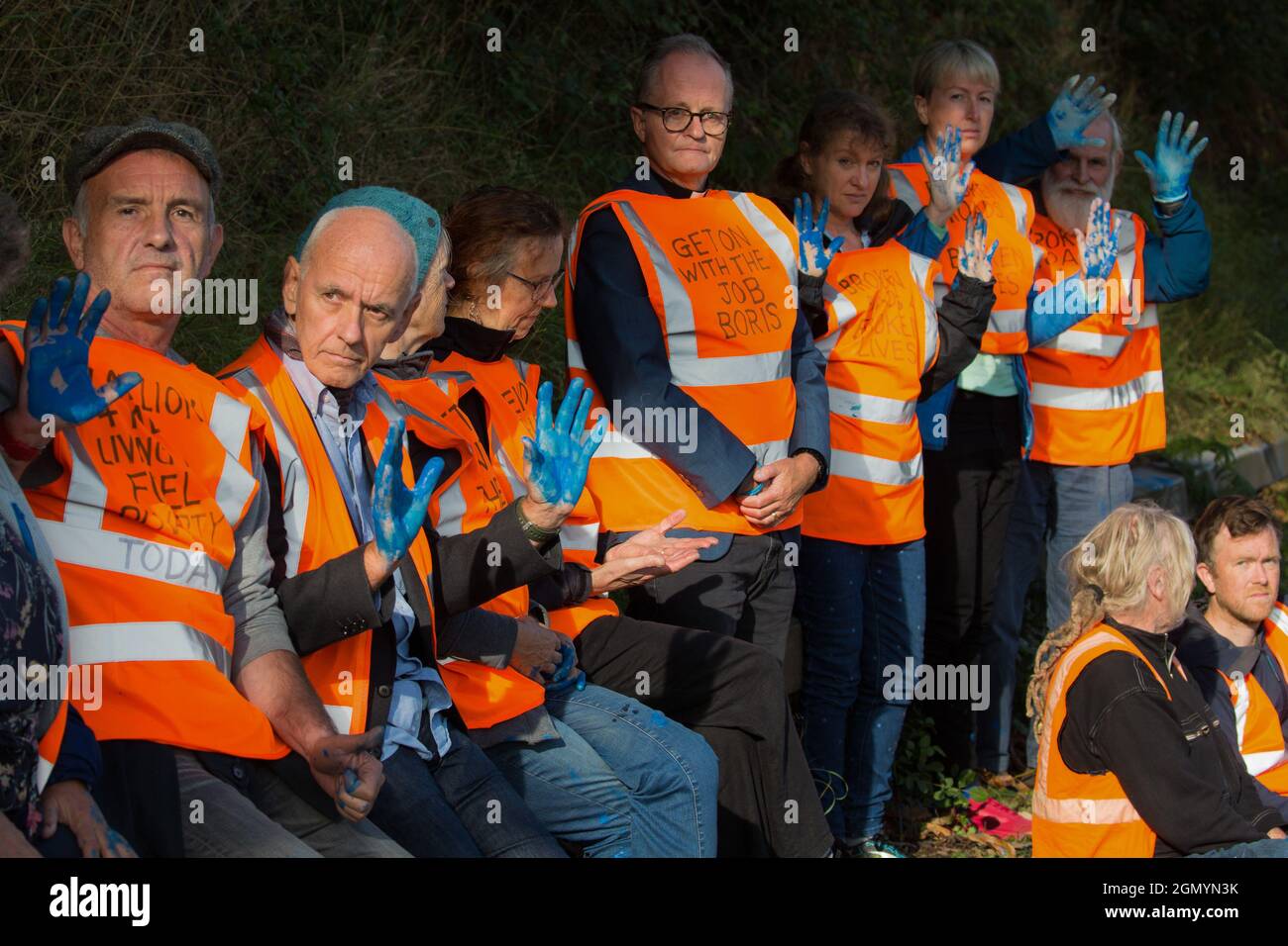 Ockham, Regno Unito. 21 Settembre 2021. Insulate gli attivisti britannici del clima tenere le mani ricoperte di vernice blu prima di essere arrestati dalla polizia di Surrey dopo aver bloccato la carreggiata in senso orario della M25 tra gli svincoli 9 e 10 come parte di una campagna volta a spingere il governo britannico a fare un cambiamento legislativo significativo per iniziare a diminuire emissioni. Entrambe le carreggiate sono state bloccate brevemente prima di essere sgombrate dalla polizia di Surrey. Gli attivisti chiedono che il governo prometta immediatamente sia di finanziare e garantire l'isolamento di tutti gli alloggi sociali in Gran Bretagna entro il 2025, sia di garantire la produttività Foto Stock