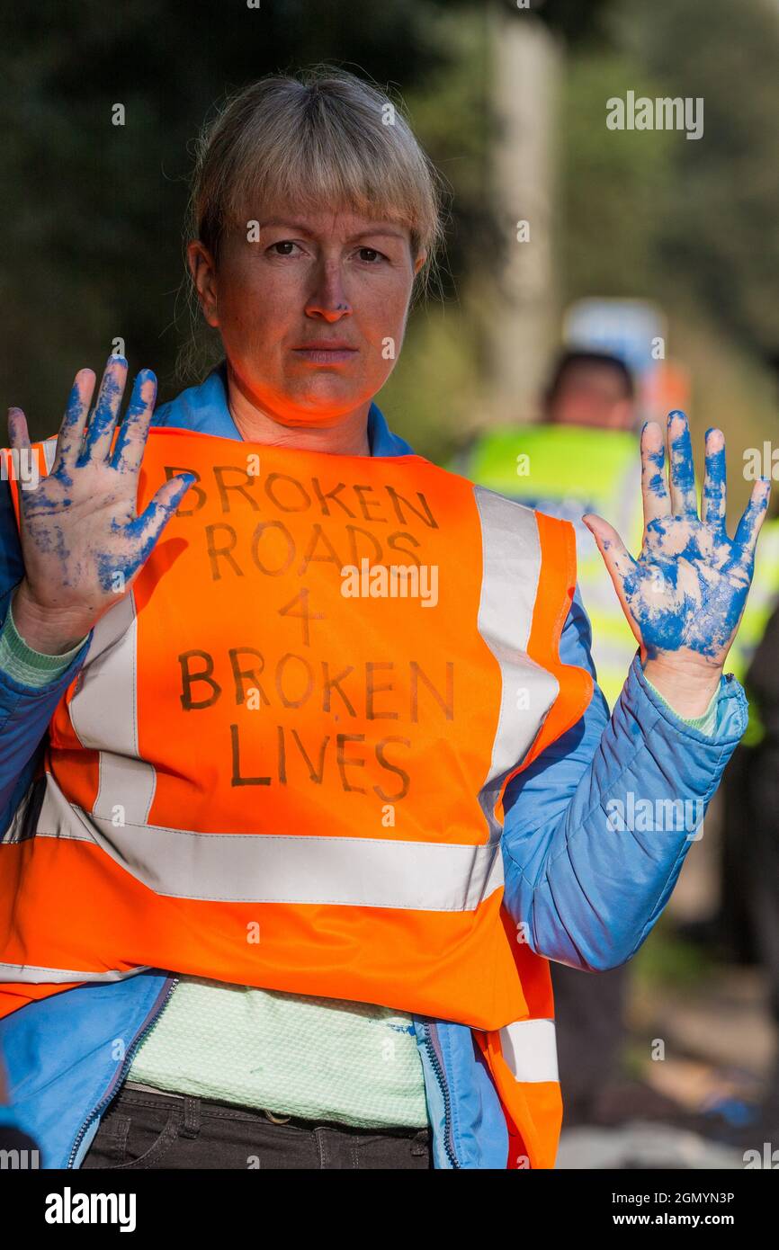 Ockham, Regno Unito. 21 Settembre 2021. Un insulato attivista britannico per il clima tiene le mani ricoperte di vernice blu prima di essere arrestato dalla polizia di Surrey dopo aver bloccato la carreggiata in senso orario della M25 tra gli svincoli 9 e 10 come parte di una campagna volta a spingere il governo britannico a fare un cambiamento legislativo significativo per iniziare riduzione delle emissioni. Entrambe le carreggiate sono state bloccate brevemente prima di essere sgombrate dalla polizia di Surrey. Gli attivisti chiedono che il governo prometta immediatamente sia di finanziare e garantire l'isolamento di tutti gli alloggi sociali in Gran Bretagna entro il 2025, sia di produ Foto Stock