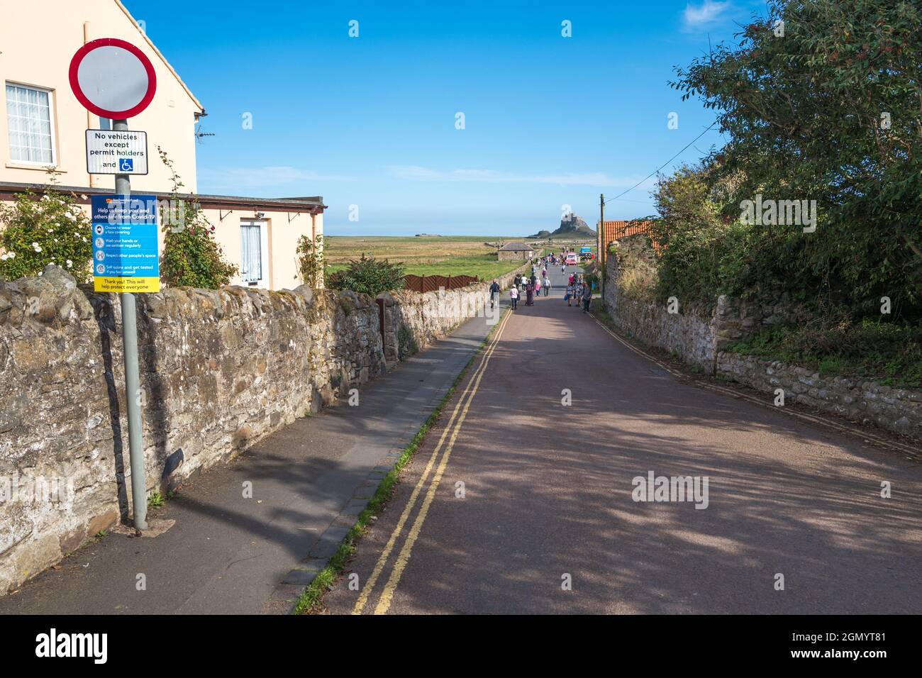 Giro turistico a piedi lungo la strada del Castello sull'Isola Santa di Lindisfarne, Northumberland, Inghilterra. Foto Stock