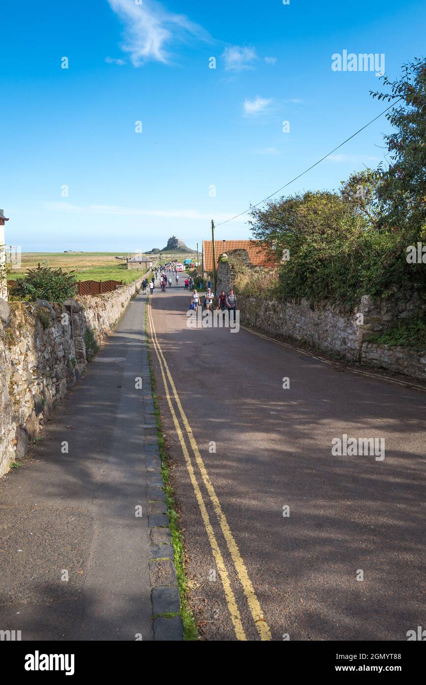 Giro turistico a piedi lungo la strada del Castello sull'Isola Santa di Lindisfarne, Northumberland, Inghilterra. Foto Stock