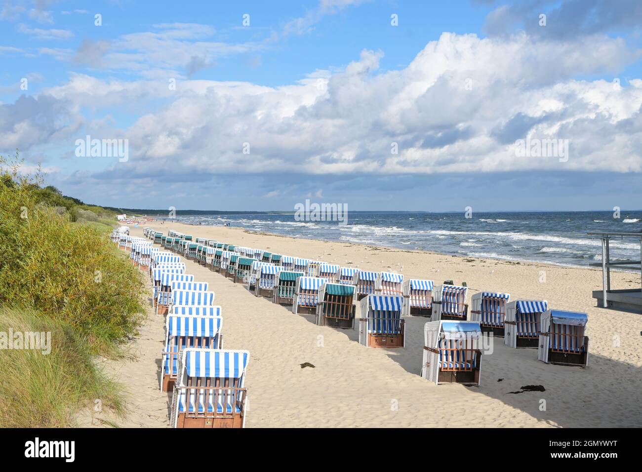 Sedie da spiaggia vuote, in Germania chiamato strandkorb, nella sabbia sulla costa del Mar Baltico, località turistica Zinnowitz sull'isola di Usedom sotto un cielo blu Foto Stock