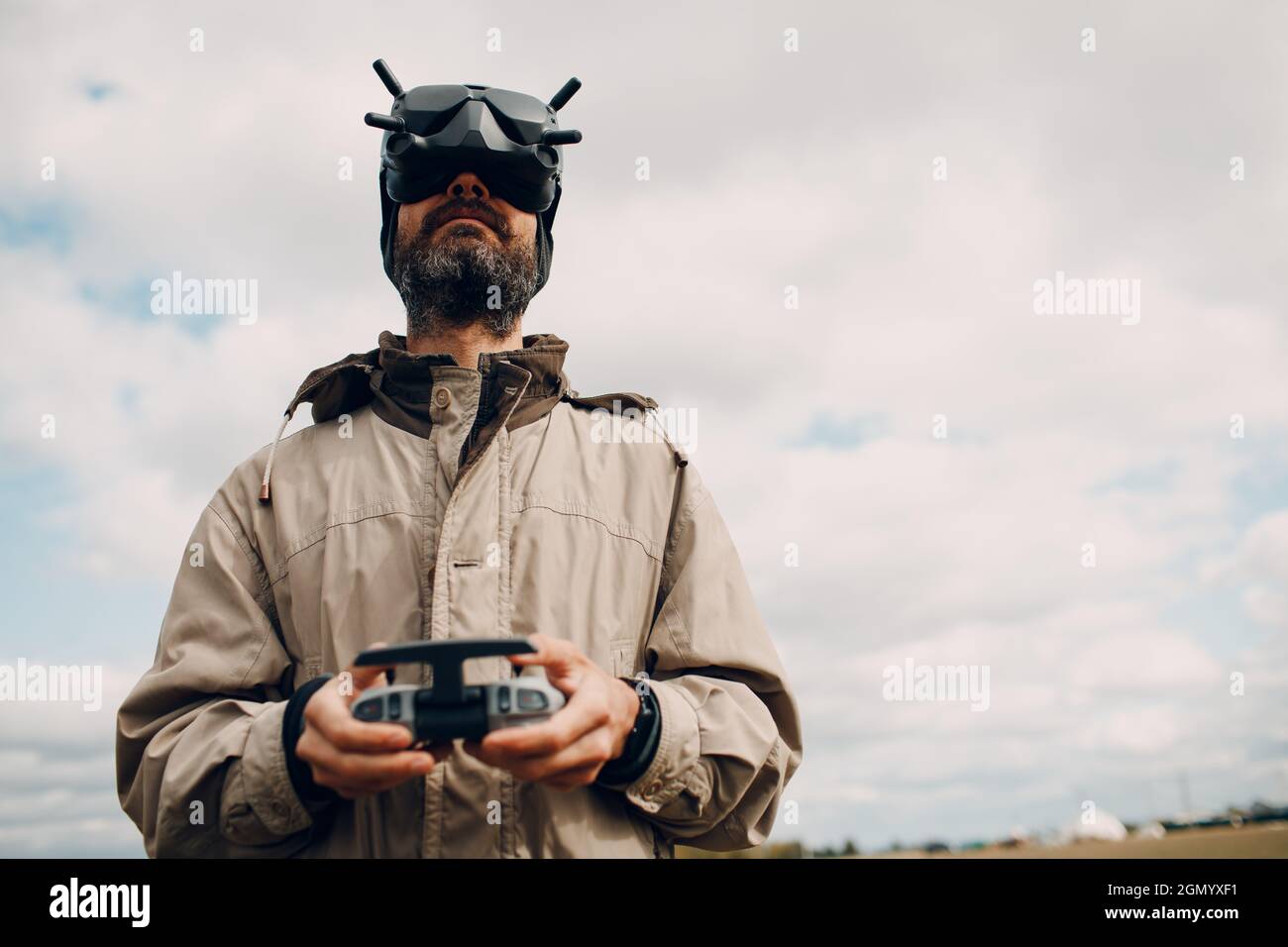 Uomo che controlla il drone quadricottero per la fotografia aerea e la videografia con occhiali antenna telecomando pad Foto Stock