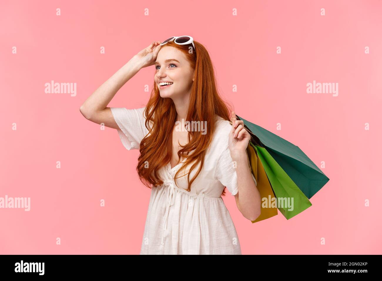 Divertito e curioso giovani redhead girl carrello stabile al interessante merci in negozio, guardando incuriosito ed interessato, sorridente come stupore di fronte shop Foto Stock