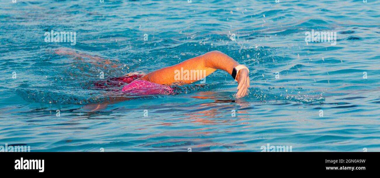 Le donne nuotano in una piscina sommerse in acqua con solo il braccio fuori dall'acqua da vicino. Foto Stock