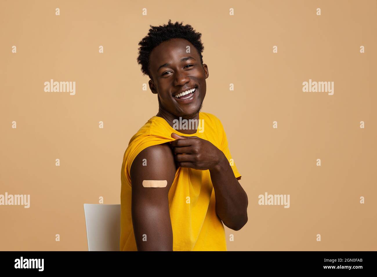 Allegro Guy Nero che mostra braccio con intonaco dopo il successo della vaccinazione di Covid-19 Shot Foto Stock