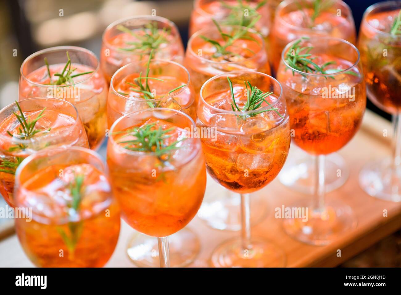 Cocktail alcolici refrigerati serviti sulle rocce con guarnitura rosmarino a righe su un tavolo a buffet in eleganti bicchieri in occasione di un evento con servizio catering Foto Stock