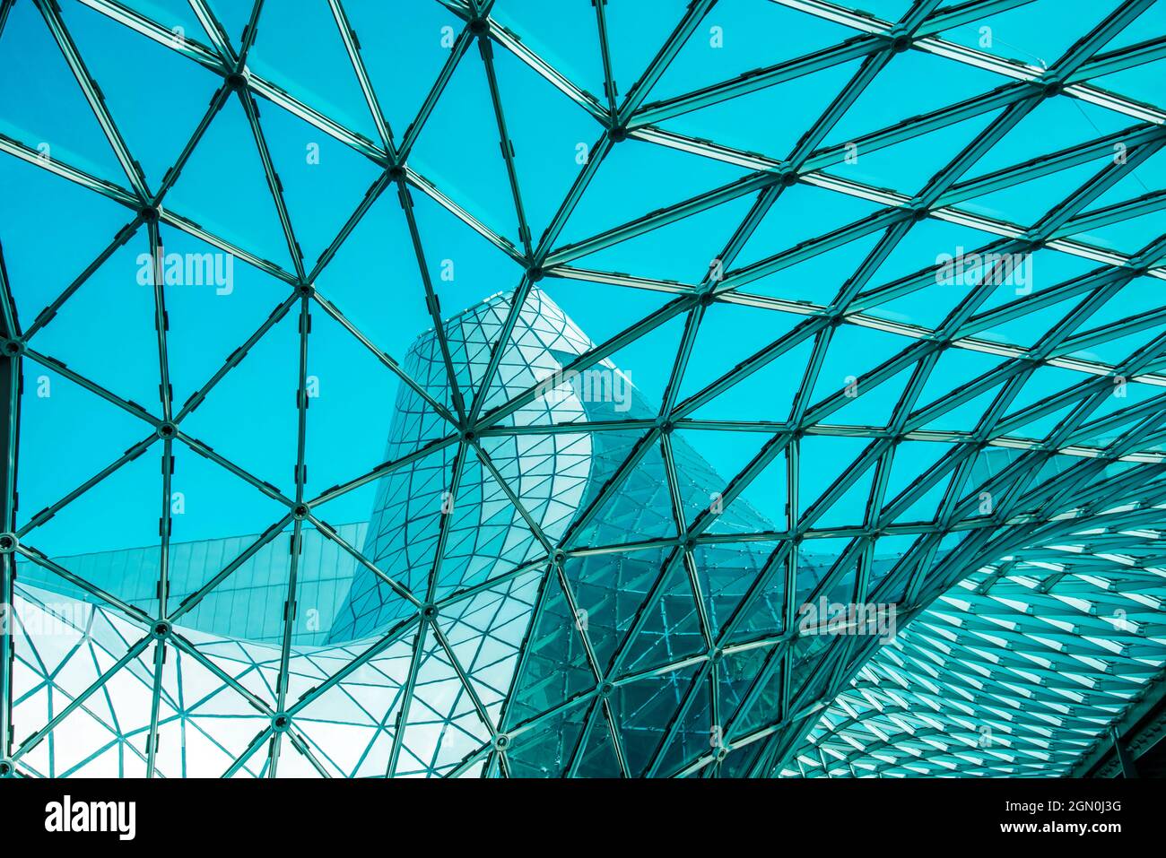 Basso angolo di tetto in vetro curvo con forme geometriche di moderno edificio progettato in stile futuristico Foto Stock