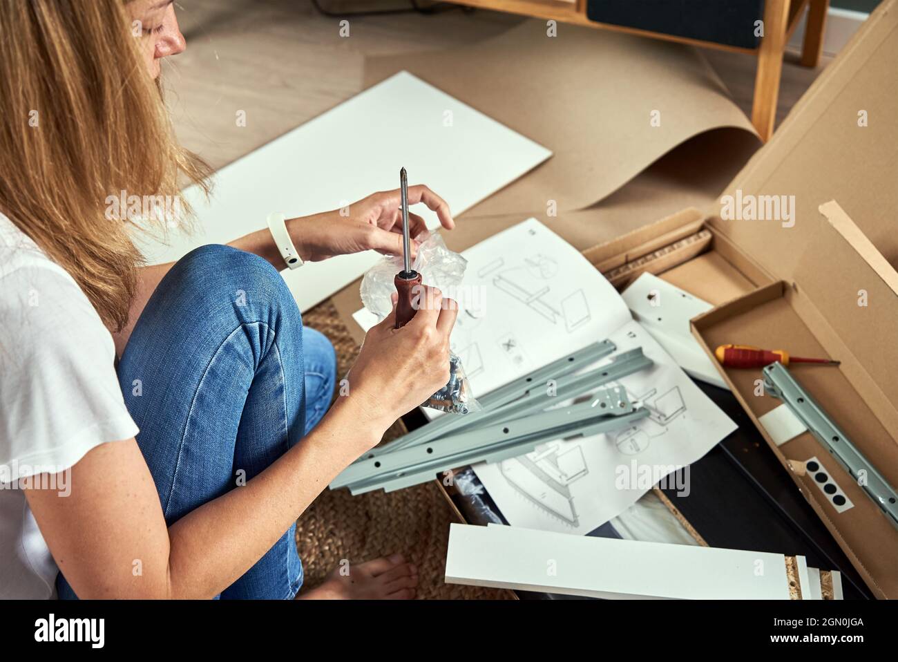 Donna che legge manuale istruzioni per assemblare mobili in soggiorno Foto Stock