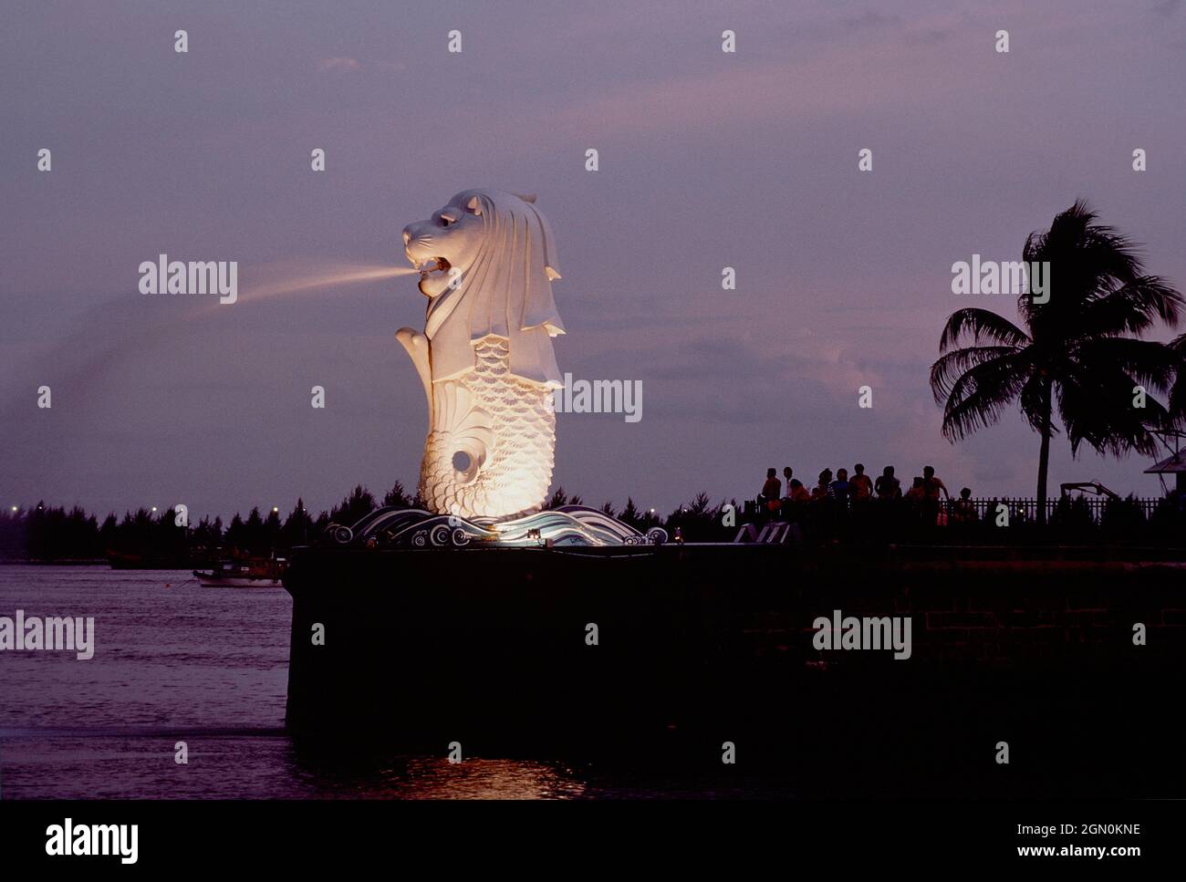 Singapore. Statua di Merlion all'ingresso del porto, illuminata di notte. Foto Stock