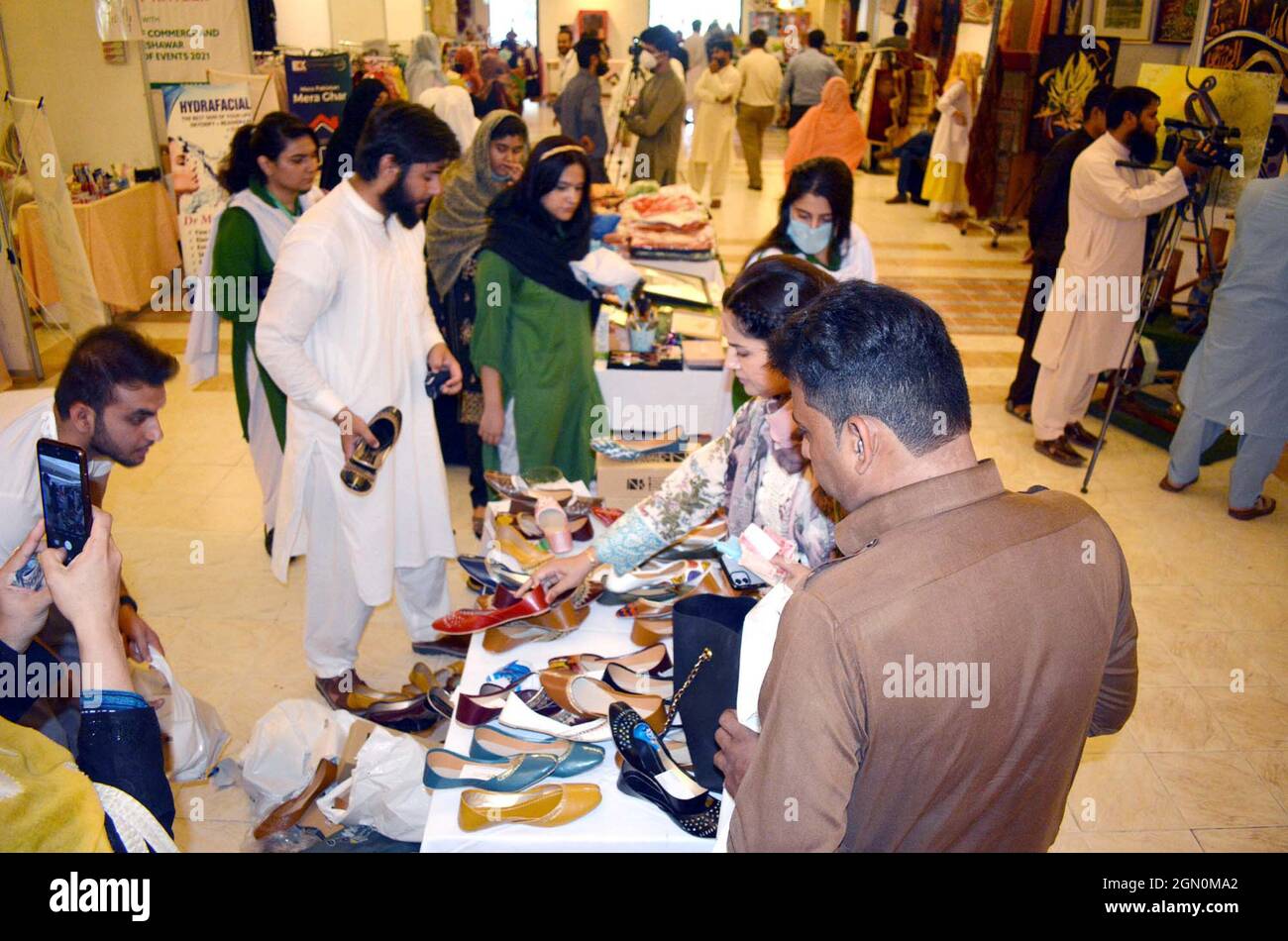 I visitatori si interessano molto alle bancarelle durante il Made in Khyber Pakhtunkhwa Exhibition Expo 2021 organizzato dalla Camera di Commercio e industria delle Donne (WCCI) che si è tenuta a Peshawar martedì 21 settembre 2021. Foto Stock