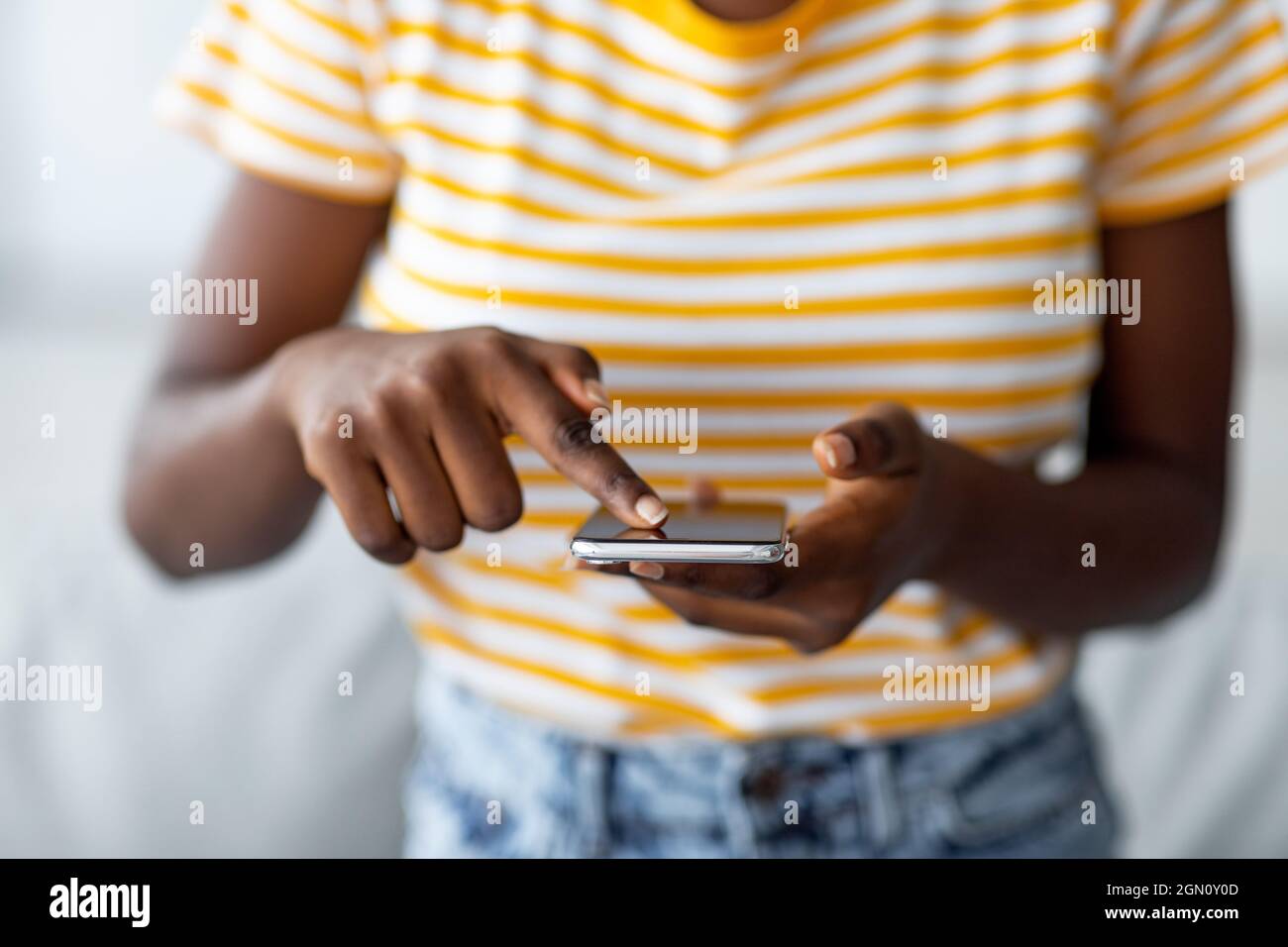 Donna nera irriconoscibile con il nuovissimo telefono cellulare Foto Stock