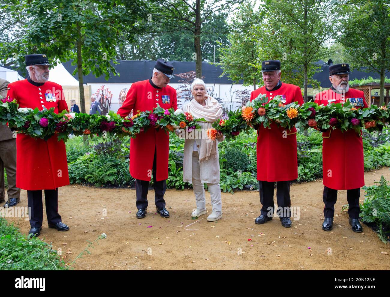 Dame Judi Dench al RHS Chelsea Flower Show in posa con i pensionati Chelsea mentre si tiene una rosa rossa. Foto Stock