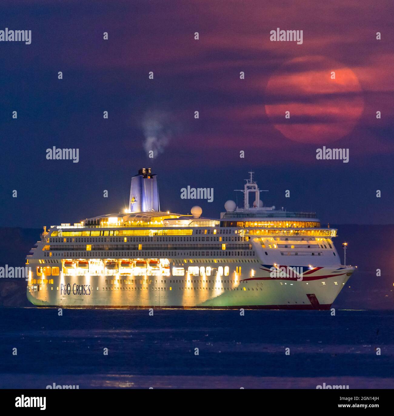 Weymouth, Dorset, Regno Unito. 21 settembre 2021. Meteo Regno Unito. La Luna piena di Harvest è oscurata da sottili alte nuvole come si alza da dietro la nave da crociera P&o Aurora che è ancorata nella baia a Weymouth in Dorset il l'ultimo giorno di estate astronomica. Picture Credit: Graham Hunt/Alamy Live News. Foto Stock