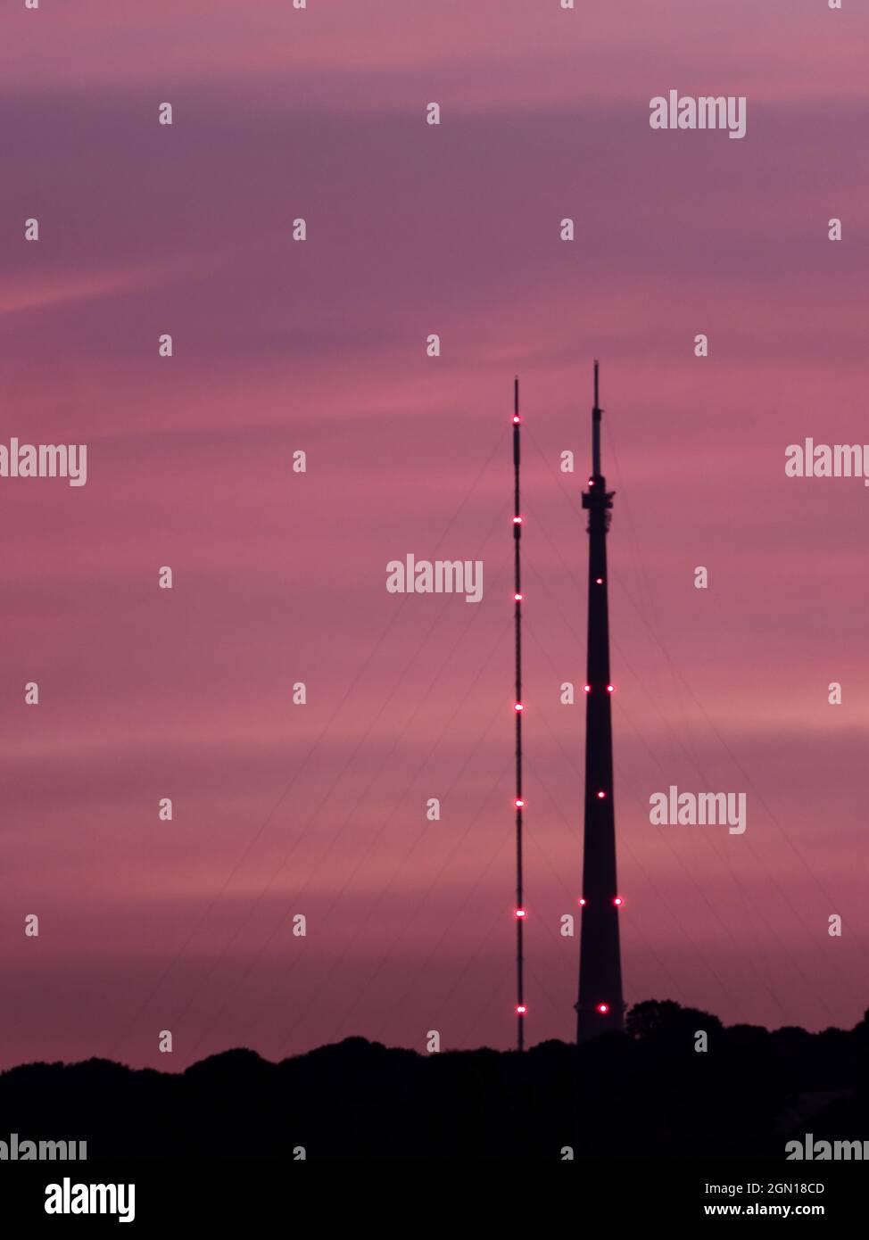 La stazione di trasmissione Emley Moor, a Wakefield, West Yorkshire, si affaccia su un tramonto viola. A sinistra si trova la torre temporanea, a destra si trova l'Arqiva to Foto Stock