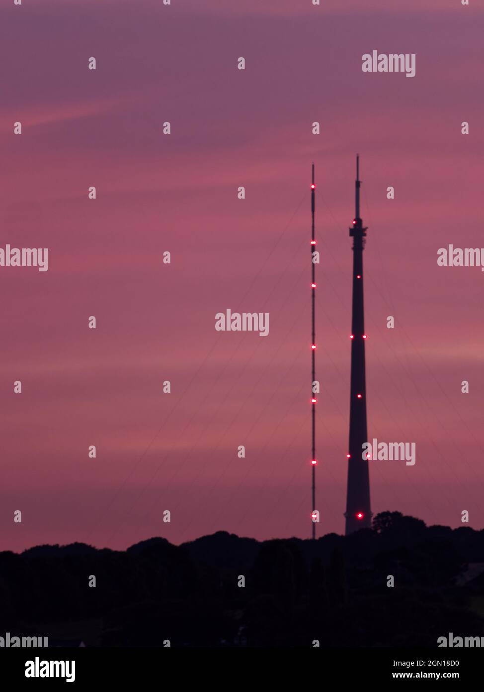 La stazione di trasmissione Emley Moor, a Wakefield, West Yorkshire, si affaccia su un tramonto viola. A sinistra si trova la torre temporanea, a destra si trova l'Arqiva to Foto Stock